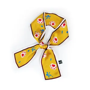 Détail de foulard en soie jaune motif patte de chat, ruban twilly étroit pour sacs et cou.