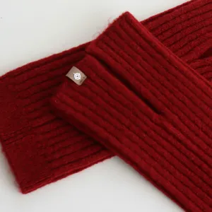 Detailopname van rode gebreide beenwarmers, met fijn ribtextuur en gezellige wollen stof.