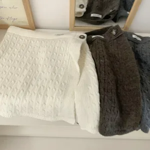 Detailansicht des Zopfmuster-Lagenrocks und vielseitigen Wickelschals mit stilvollem Design.