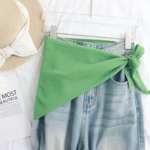 Elegante bufanda triangular de punto verde combinada con vaqueros casual de denim.