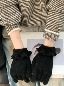 Black knitted gloves with ruffle cuff detail, cozy winter accessory close-up view.