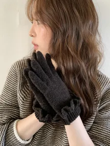 Detailed close-up shot of women's winter warm knit gloves in dark brown with ruffle cuffs.