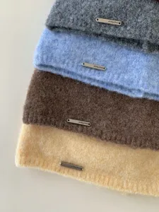 Primo piano dettagliato di comodi berretti invernali in maglia con etichette in metallo.