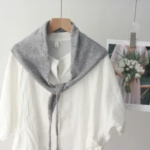 Vue detaillee d'un foulard triangulaire en tricot gris elegance sur chemisier blanc.
