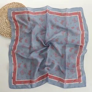 Close-up detail of the butterfly print cotton square scarf, elegant blue and red border.