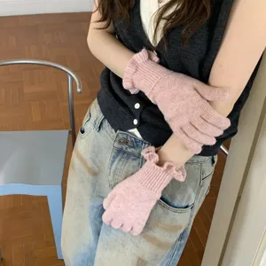 Close-up detail of women winter pink knitted gloves featuring delicate frill cuffs, cozy style.
