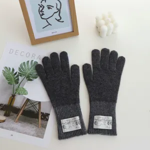 Close up detail of dark grey winter warm knitted gloves, cozy aesthetic flat lay style.
