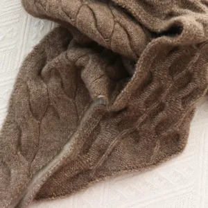 Close-up detail shot of a cozy brown cable-knit scarf showing soft texture and fine stitching.