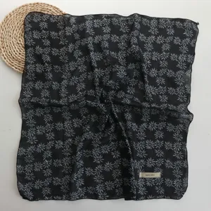 Close-up detail of the black floral square scarf showing soft fabric and daisy print.