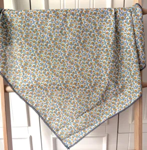 Gros plan détaillé du foulard carré en coton bleu avec motif floral jaune et bordure.