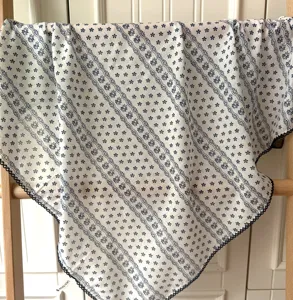 Gros plan détaillé d'un foulard carré en coton à fleurs vintage sur une échelle en bois.