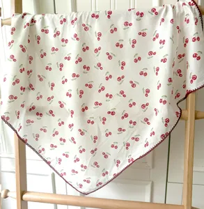 Detail en gros plan du carre de foulard en coton blanc avec imprime cerises et fine bordure.