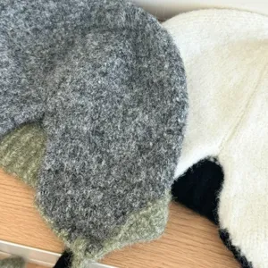 Detalle de sombrero trapper de felpa tejida muestra textura suave y orejeras.