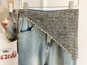 Detail view of stylish layered denim jeans with black white knit waist wrap shawl fashion.