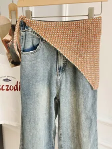 Stylish light wash denim pants paired with a chic knitted triangular waist wrap skirt.
