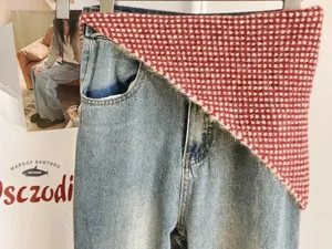 Close-up detail of knitted red white triangle scarf layered with classic denim jeans outfit.