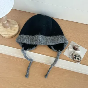 Vista detallada del gorro de invierno de punto de felpa con orejeras y cordones.