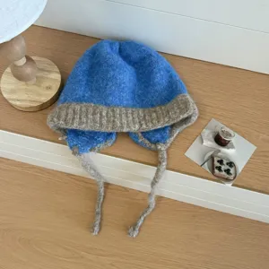 Detalle del gorro de punto azul con orejeras trenzadas y textura de felpa muy suave.