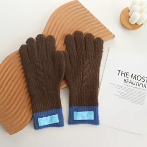 Detailed view of cozy brown knitted winter gloves featuring stylish blue ribbed cuffs.