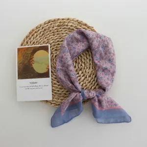 Detailed view of a soft pink floral square scarf with blue border, elegant literary neck accessory.