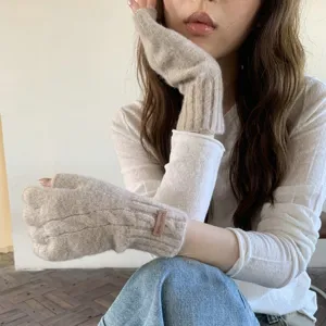 Detail shot of beige cable knit fingerless gloves featuring a handmade label for winter.