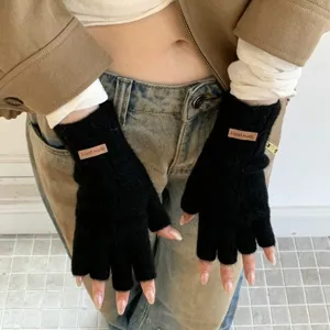 Black knit fingerless gloves detail shot showing soft texture and cute handmade leather tag.