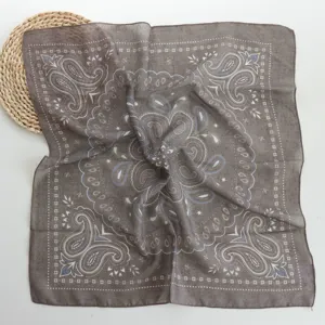 Close-up detail view of a stylish grey paisley square scarf, soft and breathable fabric.