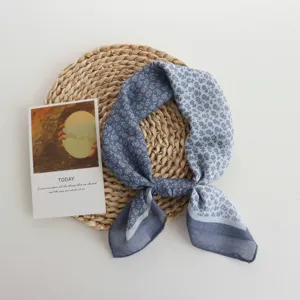 Detail view of a blue floral small scarf, featuring lightweight breathable fabric and elegant print.