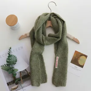 Détail écharpe en tricot vert gros plan, texture douce et confortable, accessoire d'hiver.