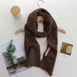Vue détaillée de l'écharpe longue en tricot marron, douce et chaude pour l'hiver classique.