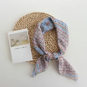 Detail view of the paisley printed square scarf featuring elegant blue and red floral patterns.