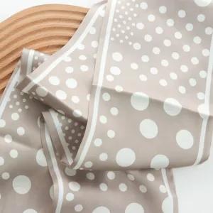 Close-up detail of a chic beige polka dot silk scarf, elegant neckerchief for stylish outfits.
