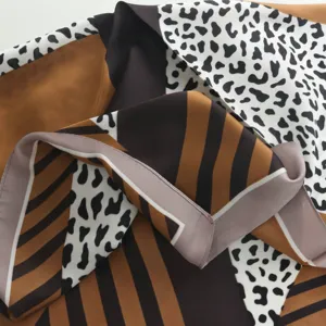 Detailweergave van een satijnen sjaaltje met chique geometrisch patroon en opvallende luipaardprint.
