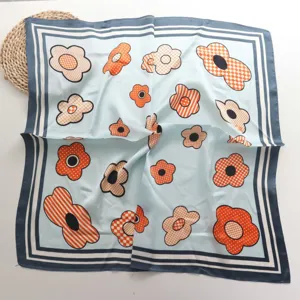Detailopname van de blauwe sjaal van satijn met oranje bloemmotieven en nette randen.