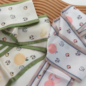 Detail van smalle zijden lint sjaal met schattige fruit- en konijnenprint. Perfect voor styling.