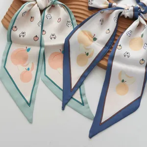 Detailopname van een smalle zijden sjaal met perzik- en konijnenprint voor dames.