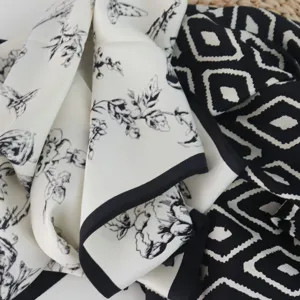 Black and white silk scarf detail, floral and geometric diamond pattern fabric texture.