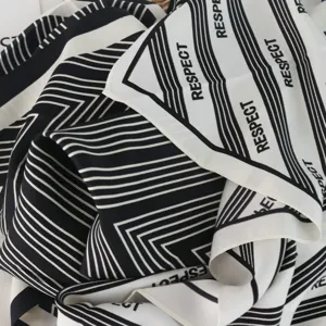 Detailed shot of a chic black and white striped triangle scarf with graphic text print.