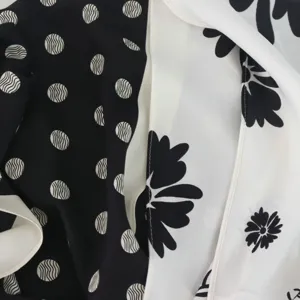 Close-up detail of black and white printed silk scarf featuring stylish polka dot and floral pattern.