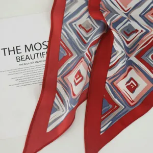 Silk triangular scarf with red border and geometric pattern for women's fashion detail.