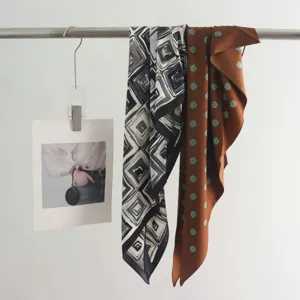 Detailed shot of stylish geometric and polka dot silk scarves hanging on rod for fashion styling.
