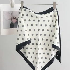 Detailed view of a cream white silk scarf with black borders and polka dots, elegant accessory.