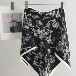 Detailed view of a stylish black and white floral silk scarf hanging neatly on display.
