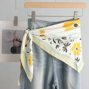 Detail shot of stylish denim jeans paired with a chic floral silk triangle scarf waist accessory.