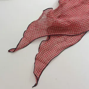 Detail des karierten Leinentuch-Dreiecks, rot-weißes Vichy-Muster mit welligem Rand.