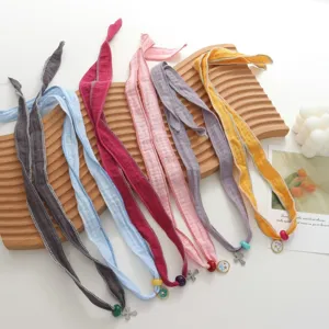 Detail view of colorful thin silk scarf necklaces with cute pendants, stylish daily accessory.