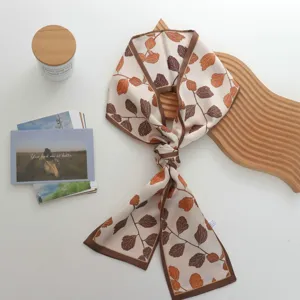 Gedetailleerd overzicht van een chique zijden sjaal met herfstbladeren print, twilly.