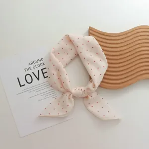 Detailed shot of a chic pink polka dot small scarf, elegant neck ribbon or stylish headband.