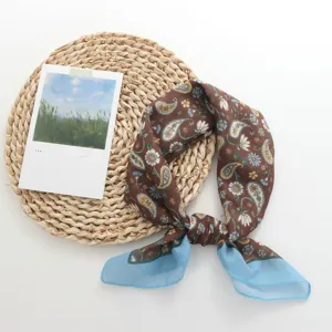 Detailopname van de kleine paisley print zijden sjaal met blauwe rand als accessoire.