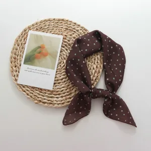 Detailed view of a retro brown polka dot square scarf, perfect for stylish neck styling.